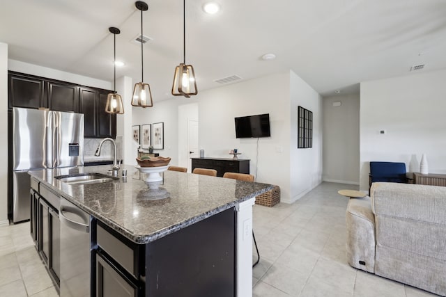 342 Meredith Dr, Fate, TX 75087 - kitchen featuring a sink, appliances with stainless steel finishes, open floor plan, dark stone countertops, and a kitchen island with sink