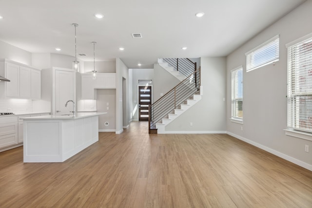 4516 Rustic Ridge Dr, Mckinney, TX 75071 - kitchen with light countertops, light wood-style flooring, white cabinetry, recessed lighting, and a center island with sink