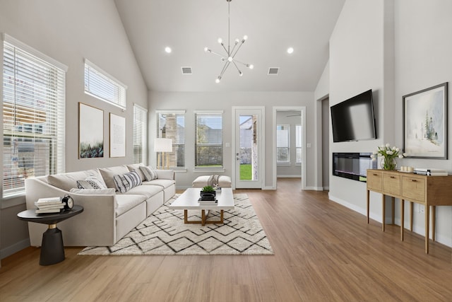 4516 Rustic Ridge Dr, Mckinney, TX 75071 - living area with high vaulted ceiling, wood finished floors, a chandelier, a glass covered fireplace, and recessed lighting