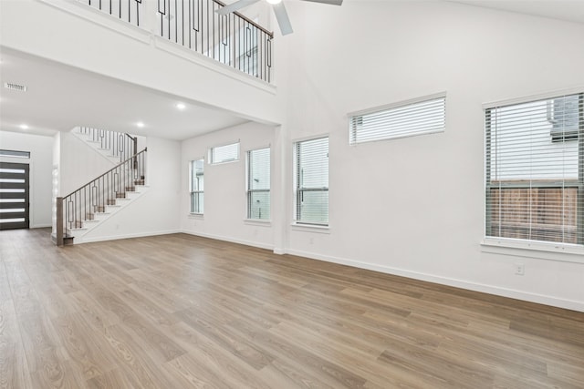 4516 Rustic Ridge Dr, Mckinney, TX 75071 - unfurnished living room featuring wood finished floors, stairway, a high ceiling, and ceiling fan