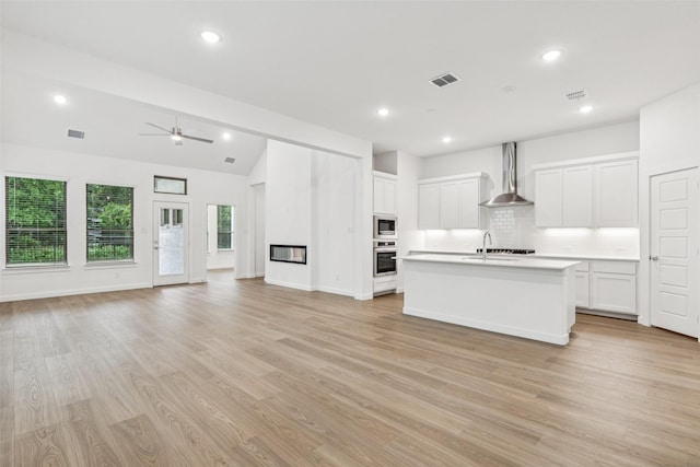 4516 Rustic Ridge Dr, Mckinney, TX 75071 - kitchen featuring wall chimney range hood, open floor plan, appliances with stainless steel finishes, tasteful backsplash, and light countertops