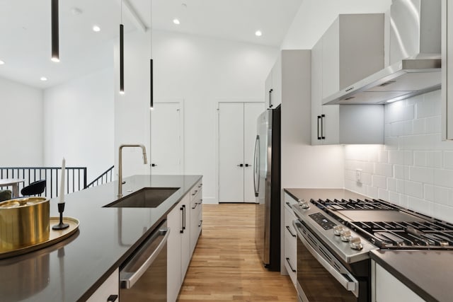 2142 Lovedale Ave Unit 101, Dallas, TX 75235 - kitchen featuring dark countertops, a sink, light wood-type flooring, stainless steel appliances, and wall chimney exhaust hood