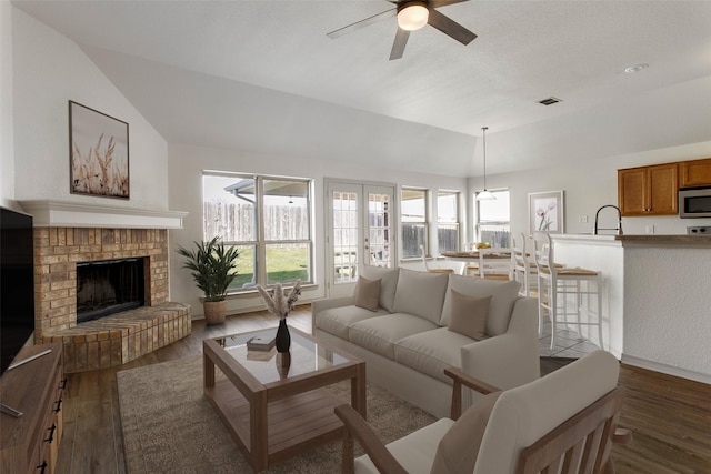 living room featuring ceiling fan, baseboards, wood finished floors, and lofted ceiling