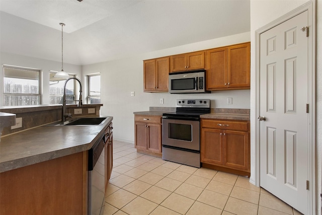 kitchen featuring light tile patterned flooring, dark countertops, brown cabinets, stainless steel appliances, and a sink