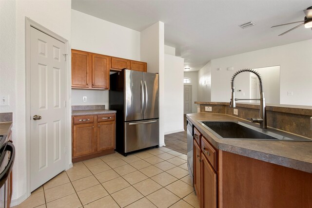 kitchen featuring a ceiling fan, visible vents, brown cabinets, stainless steel appliances, and a sink