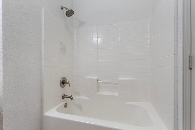 bathroom with a textured wall and washtub / shower combination