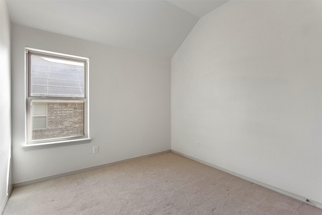 carpeted empty room with baseboards and vaulted ceiling