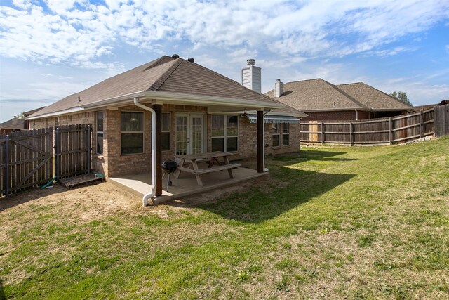 rear view of house featuring a patio area, a fenced backyard, french doors, and a lawn