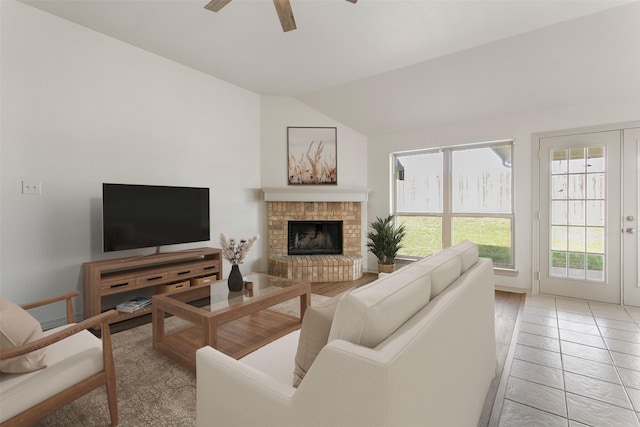 living room featuring a fireplace, a ceiling fan, and vaulted ceiling