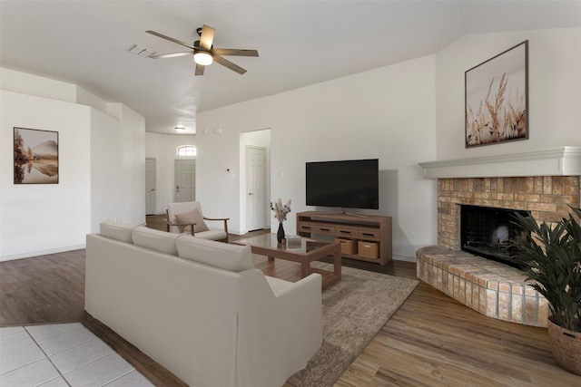 living area featuring visible vents, a brick fireplace, ceiling fan, wood finished floors, and lofted ceiling