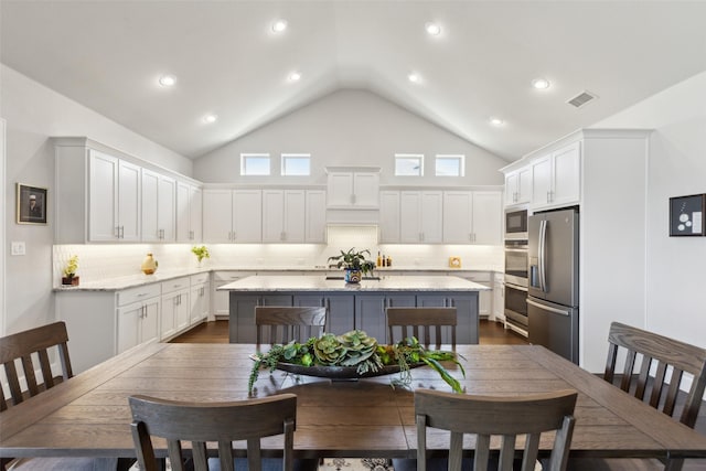 dining space featuring dark wood-type flooring, high vaulted ceiling, and visible vents