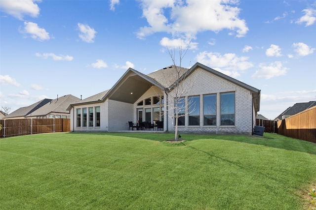 rear view of property featuring a fenced backyard, a patio, brick siding, and a yard