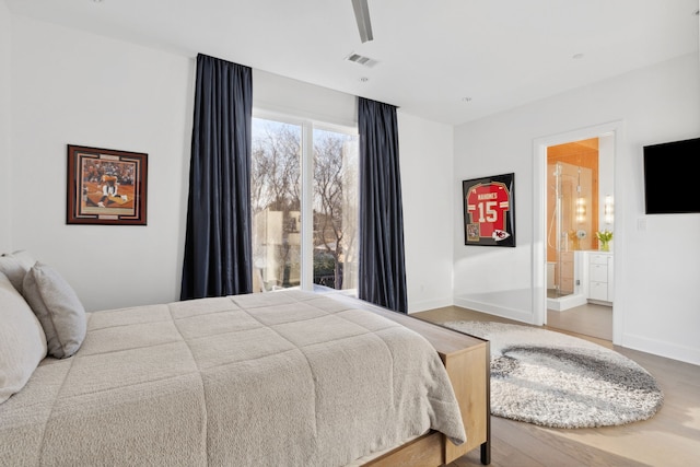 bedroom with wood finished floors, ensuite bathroom, baseboards, and visible vents