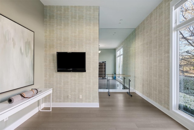 interior space featuring wood finished floors, baseboards, wallpapered walls, and a wealth of natural light