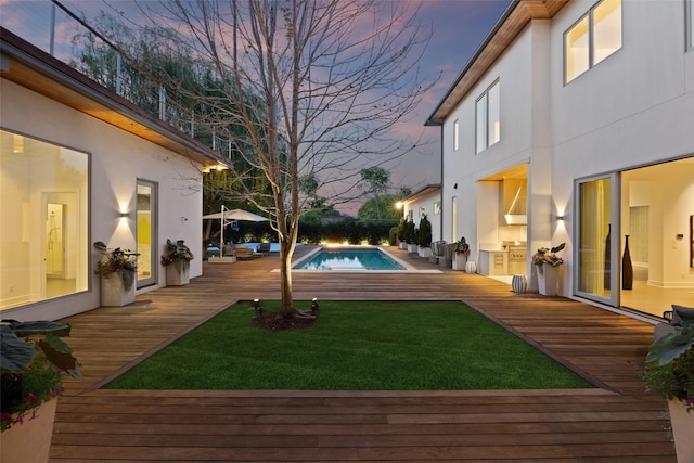 yard at dusk with an outdoor pool and a deck