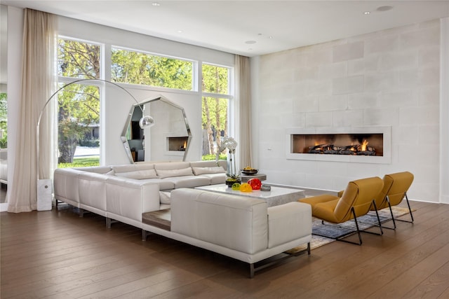 living room with dark wood-type flooring, a tile fireplace, and a healthy amount of sunlight