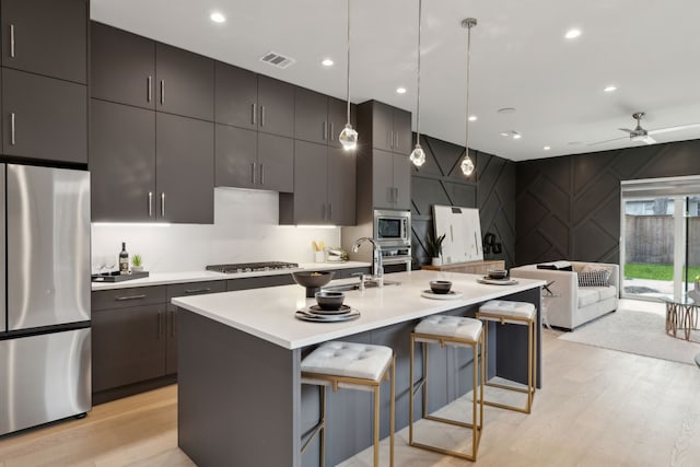 2228 Wycliff Ave, Dallas, TX 75219 - kitchen with light countertops, a kitchen bar, light wood-style floors, and appliances with stainless steel finishes