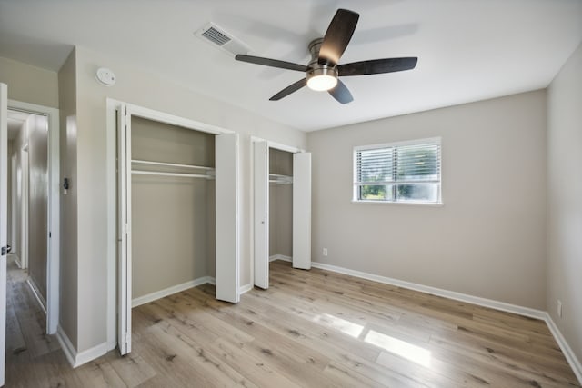 unfurnished bedroom with baseboards, multiple closets, light wood finished floors, ceiling fan, and visible vents