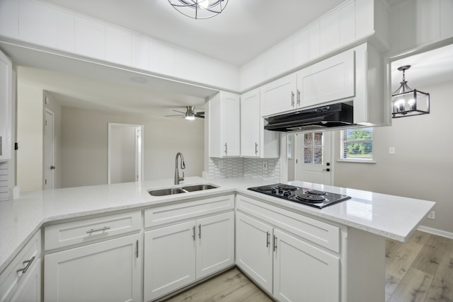kitchen featuring a sink, white cabinetry, a peninsula, black electric cooktop, and under cabinet range hood