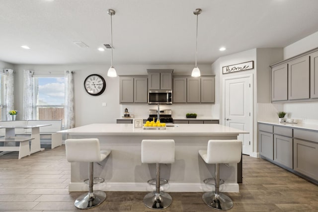 14520 Caelum Dr, Haslet, TX 76052 - kitchen featuring appliances with stainless steel finishes, gray cabinetry, a kitchen breakfast bar, and recessed lighting