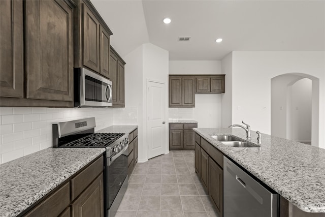 919 Madeline Ln, Cleburne, TX 76033 - kitchen with stainless steel appliances, a sink, arched walkways, backsplash, and light stone countertops
