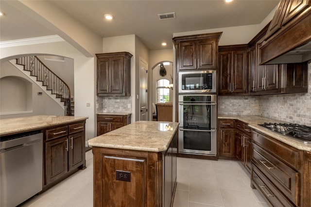 1413 Artesia Ln, Mclendon Chisholm, TX 75032 - kitchen with light stone counters, arched walkways, stainless steel appliances, custom range hood, and visible vents
