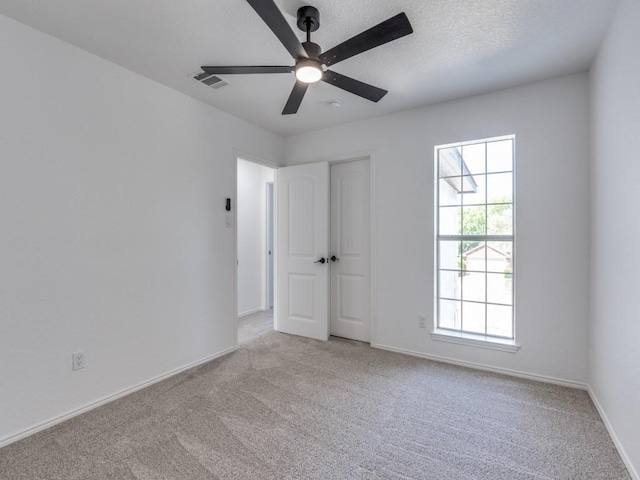 carpeted spare room featuring a ceiling fan, baseboards, and visible vents