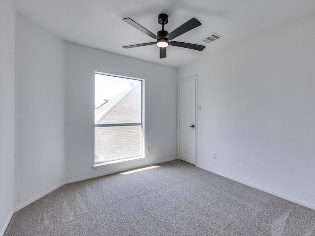 carpeted empty room featuring baseboards, a ceiling fan, and visible vents