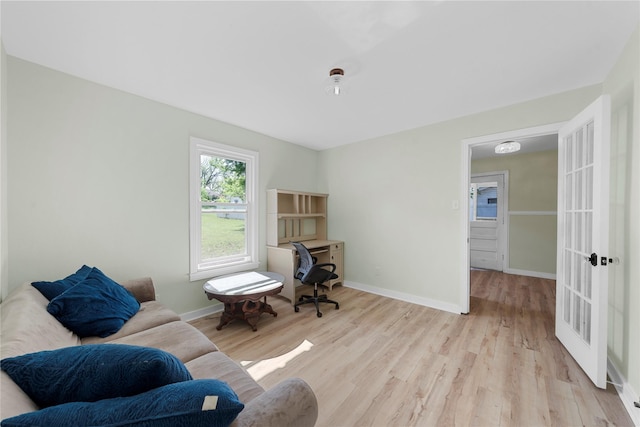 office space featuring baseboards, french doors, and light wood-type flooring