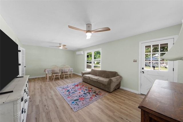 living room featuring a wall mounted air conditioner, ceiling fan, baseboards, and light wood-type flooring