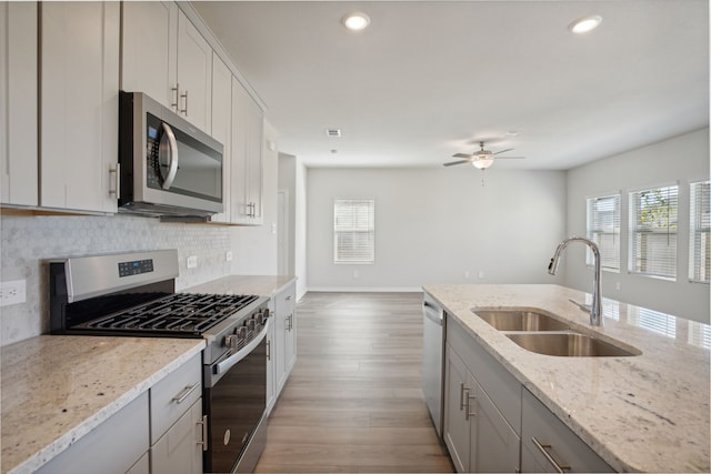 3910 Walmer Way, Princeton, TX 75071 - kitchen with stainless steel appliances, a sink, tasteful backsplash, a ceiling fan, and light wood-style flooring