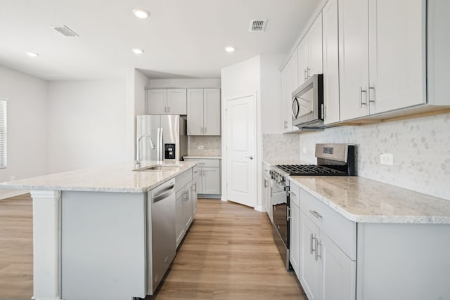 3910 Walmer Way, Princeton, TX 75071 - kitchen featuring stainless steel appliances, a sink, light wood-type flooring, backsplash, and light stone countertops
