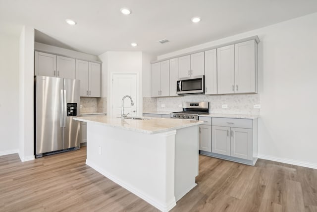 3910 Walmer Way, Princeton, TX 75071 - kitchen with stainless steel appliances, a sink, a kitchen island with sink, light wood-style flooring, and recessed lighting