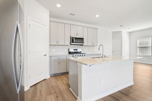3910 Walmer Way, Princeton, TX 75071 - kitchen with stainless steel appliances, a sink, gray cabinetry, light wood finished floors, and decorative backsplash