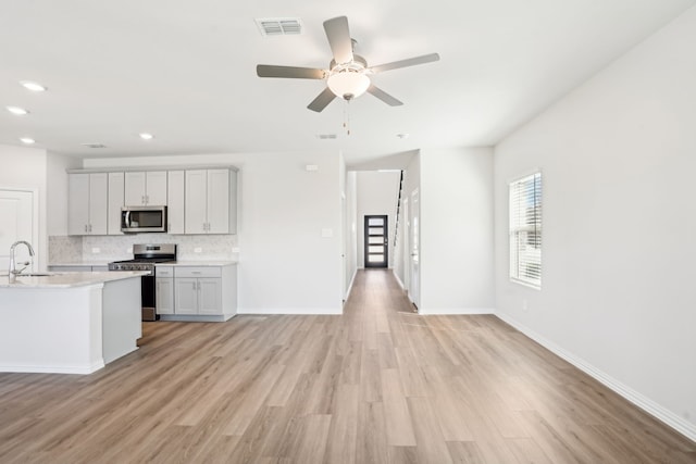 3910 Walmer Way, Princeton, TX 75071 - kitchen featuring stainless steel appliances, a sink, decorative backsplash, light countertops, and light wood finished floors