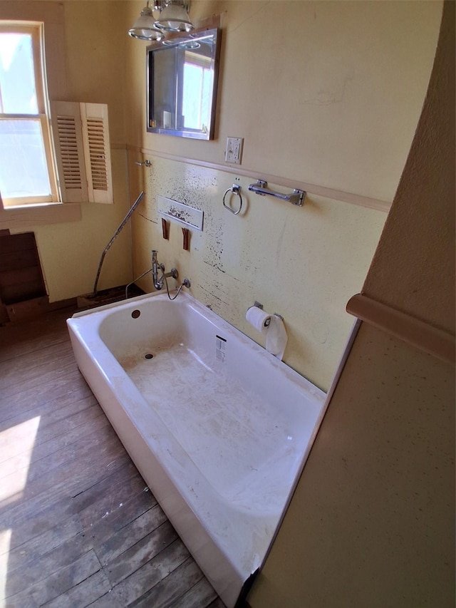 208 E 4th St, Coleman, TX 76834 - bathroom with a wealth of natural light, a bathing tub, and wood finished floors