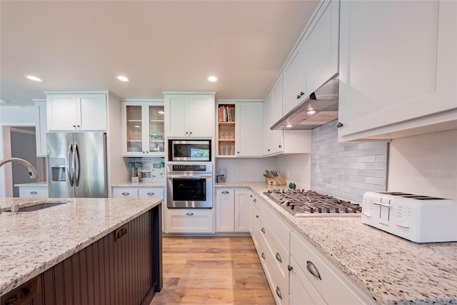 kitchen featuring light wood-style flooring, open shelves, under cabinet range hood, appliances with stainless steel finishes, and a sink