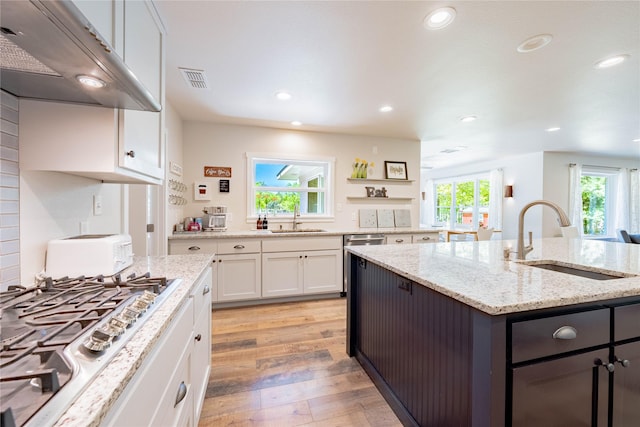 kitchen featuring a sink, white cabinets, stainless steel gas stovetop, and under cabinet range hood