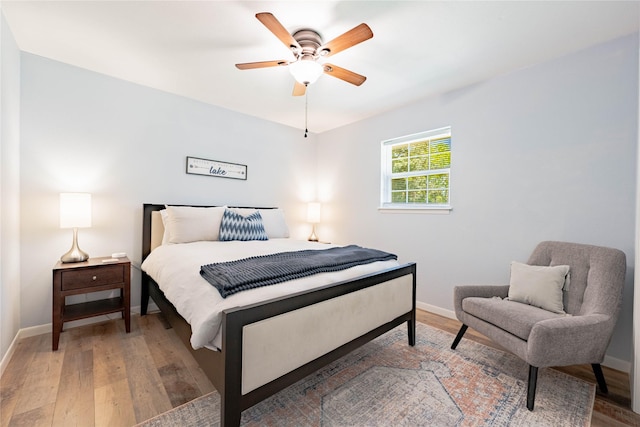 bedroom with light wood-style flooring, baseboards, and a ceiling fan
