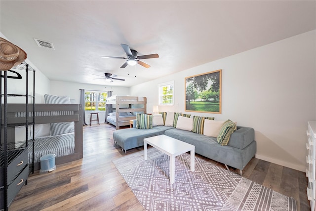 living room featuring visible vents, baseboards, a ceiling fan, and wood-type flooring