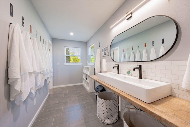 full bath with tile patterned floors, baseboards, a sink, and decorative backsplash