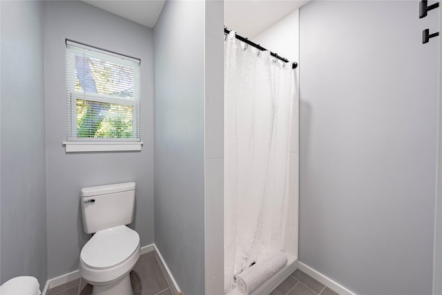 bathroom with toilet, tile patterned floors, a shower with shower curtain, and baseboards