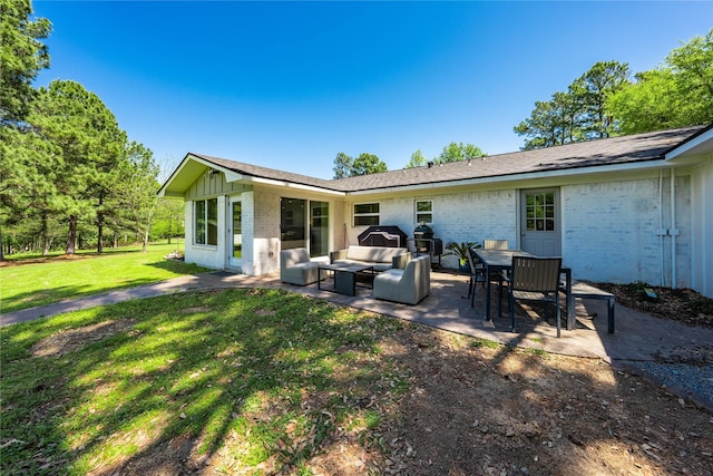rear view of property with a yard, outdoor dining area, a patio, an outdoor hangout area, and brick siding