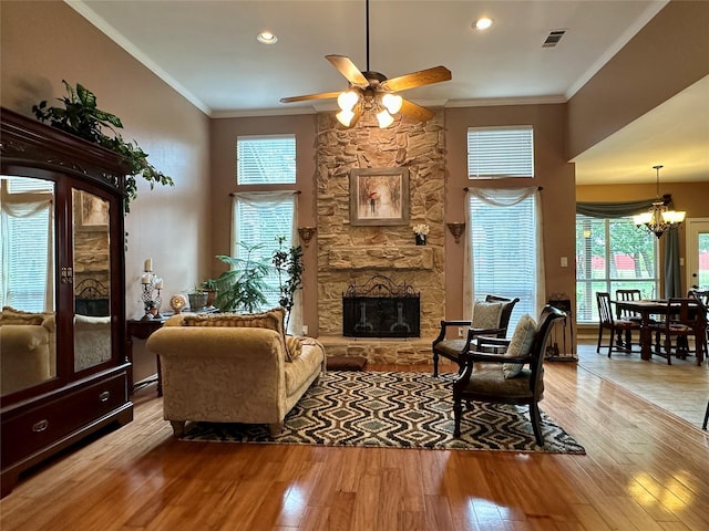 2610 Jakes Ct, Midlothian, TX 76065 - living room with crown molding, ceiling fan, a chandelier, light wood-style flooring, and a stone fireplace