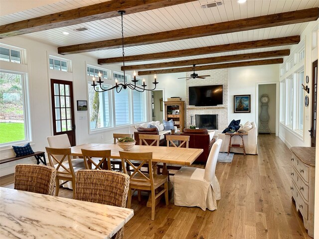 712 Camp Cypress Trl, Winnsboro, TX 75494 - dining area featuring a fireplace, visible vents, ceiling fan with notable chandelier, beamed ceiling, and light wood-style floors
