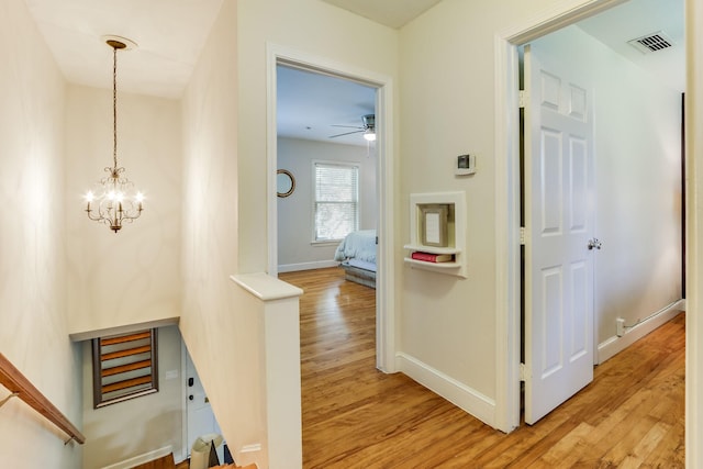 6345 Bordeaux Ave, Dallas, TX 75209 - hall with light wood-type flooring, a notable chandelier, baseboards, and visible vents