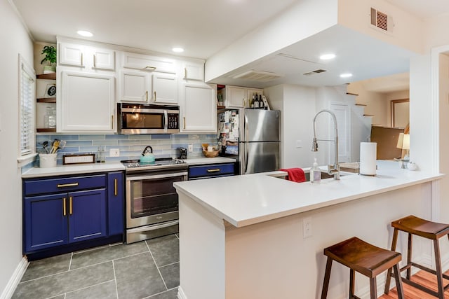 6345 Bordeaux Ave, Dallas, TX 75209 - kitchen with visible vents, a breakfast bar, blue cabinetry, stainless steel appliances, and white cabinetry
