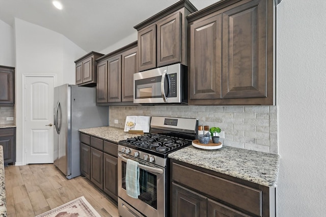 kitchen with stainless steel appliances, dark brown cabinetry, light wood-style floors, and decorative backsplash