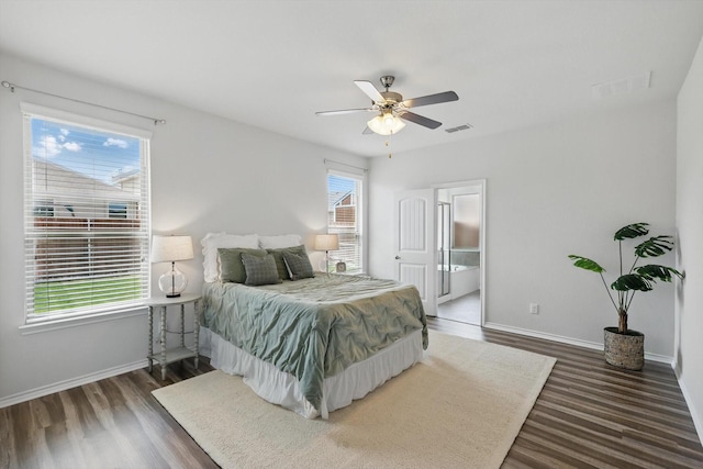bedroom with visible vents, baseboards, ensuite bathroom, and wood finished floors