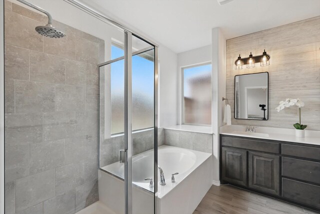 bathroom featuring a shower stall, vanity, a bath, and wood finished floors